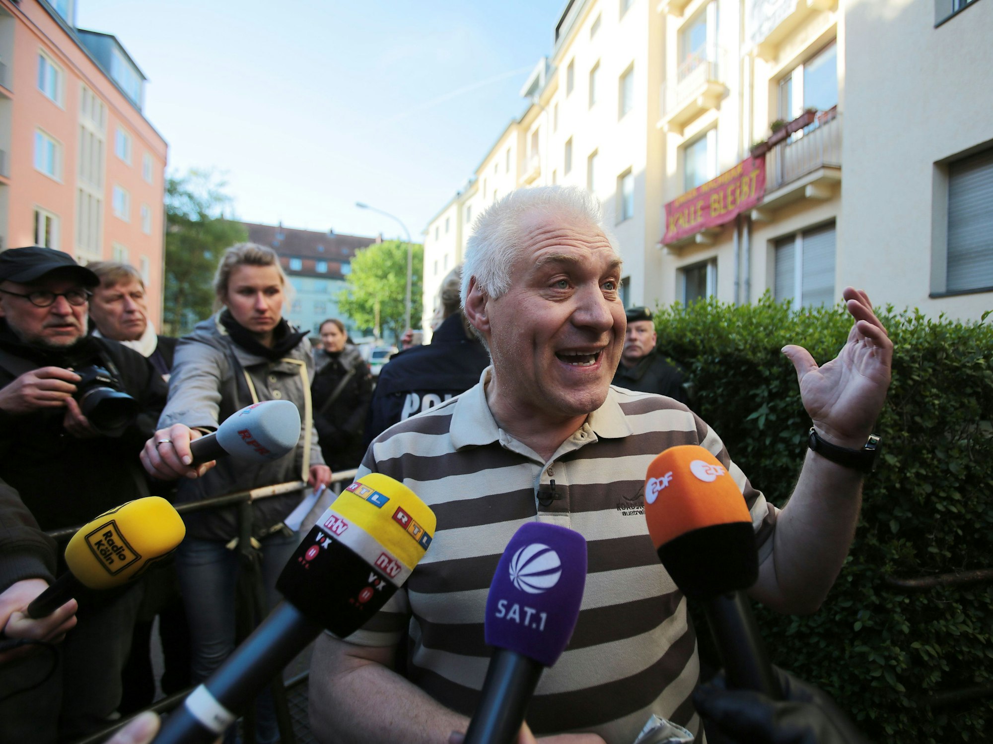 Ein Mann redet mit Journalisten, die Mikrofone halten.