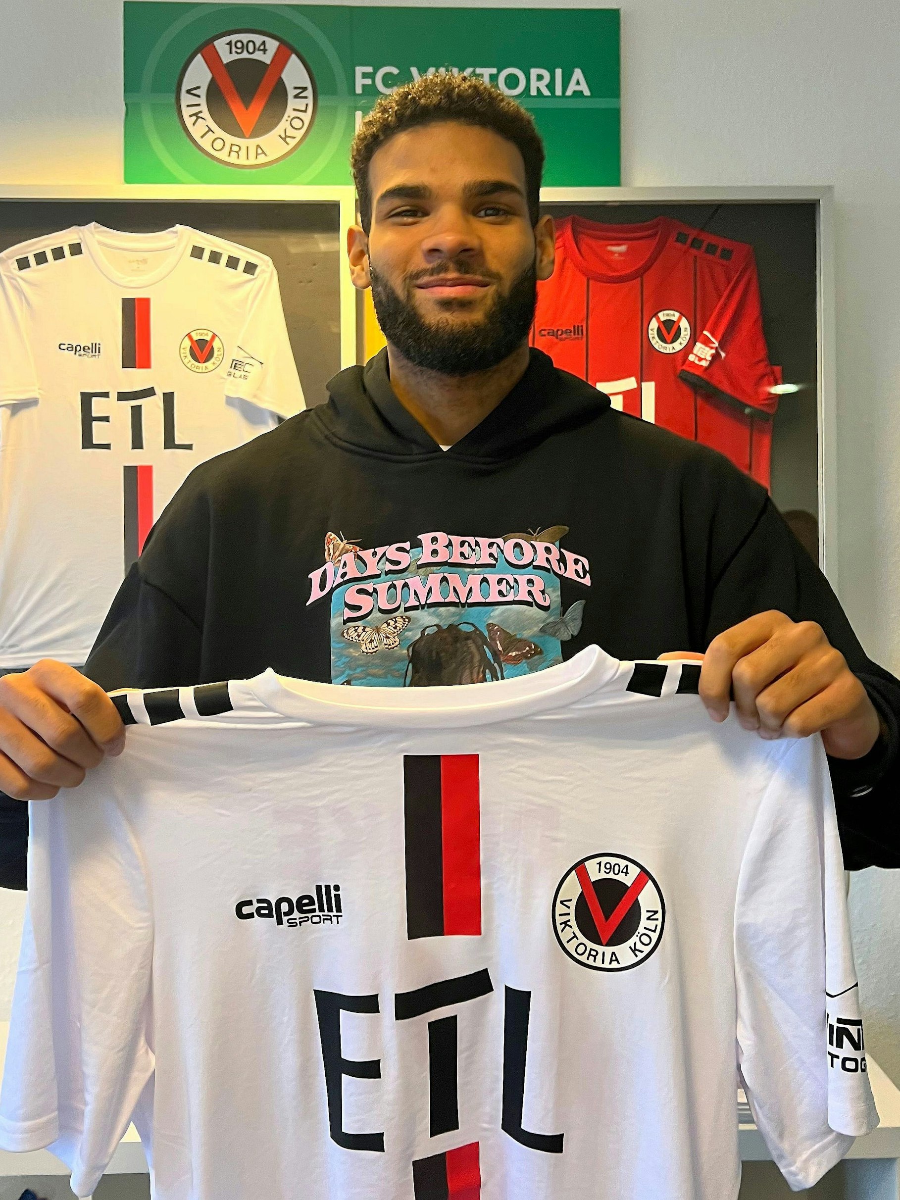 Jamal Siebert zeigt sein Trikot von Viktoria Köln