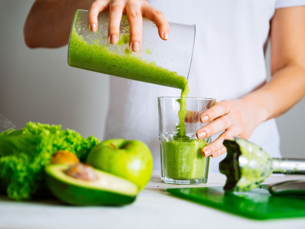Eine Frau mixt einen grünen Smoothie.
