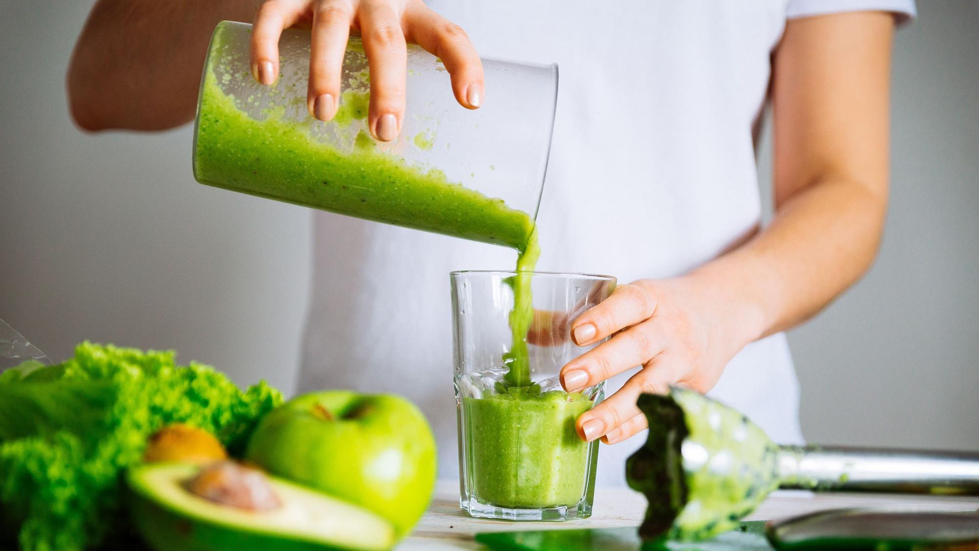 Eine Frau mixt einen grünen Smoothie.