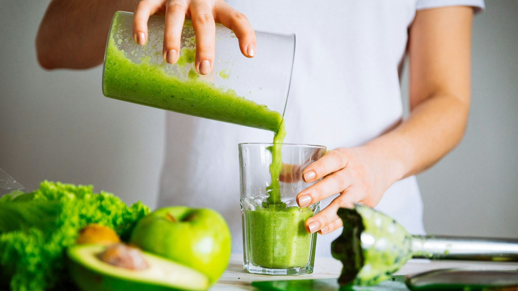 Eine Frau mixt einen grünen Smoothie.
