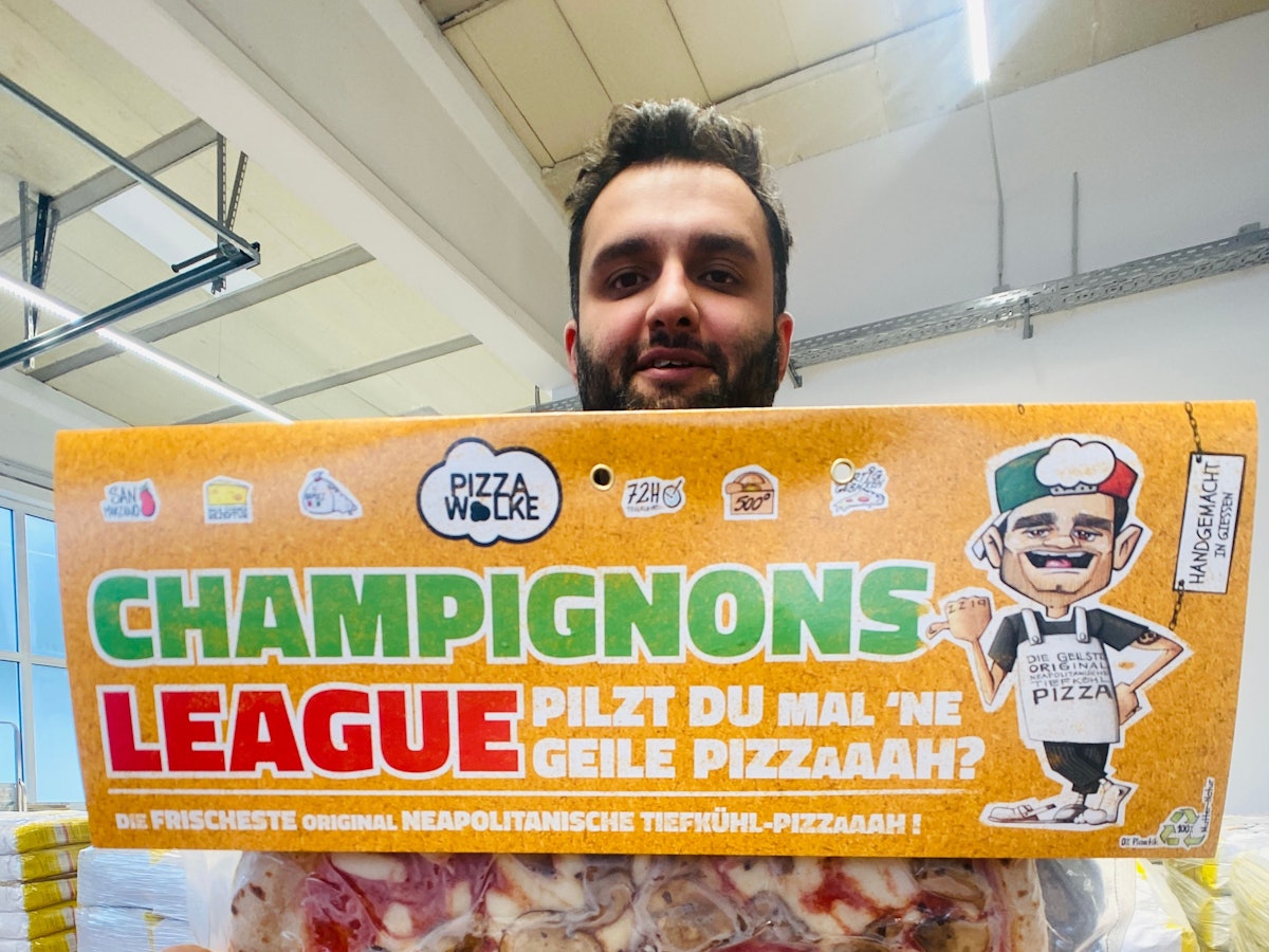 Shadi Souri hält eine Pizza in die Kamera.