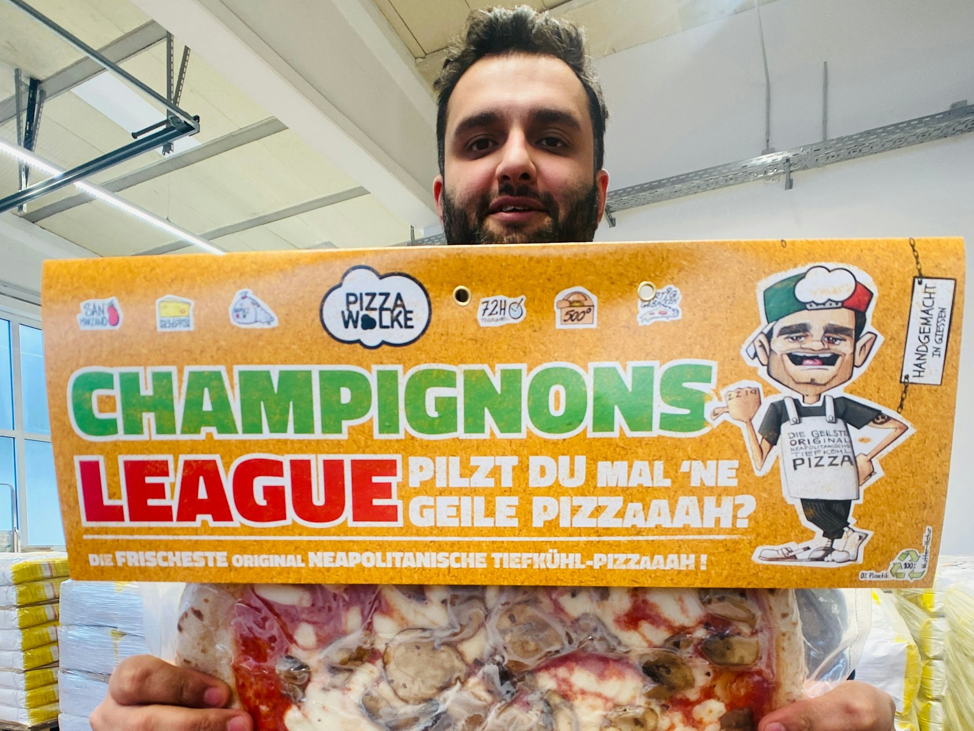 Shadi Souri hält eine Pizza in die Kamera.