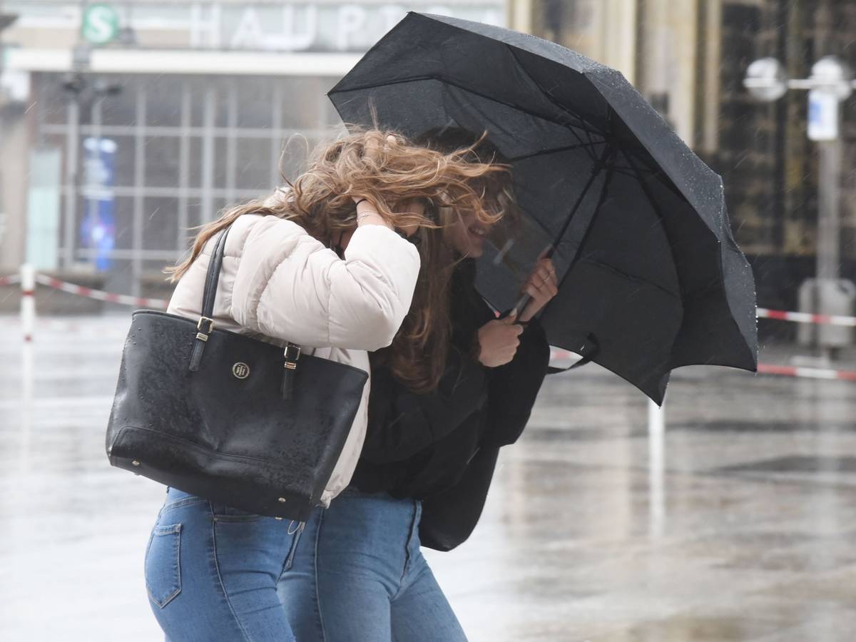 Passanten rund um den Dom kämpfen gegen Wind und Regen.