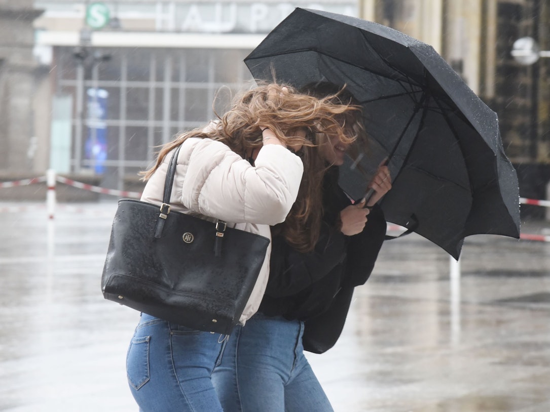 Passanten rund um den Dom kämpfen gegen Wind und Regen.