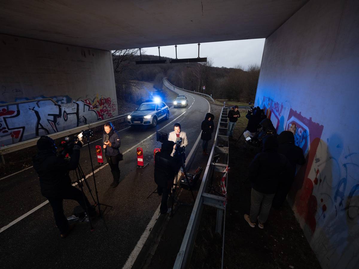 Medienvertreter stehen an einer Absperrung an der Kreisstraße 22 rund einen Kilometer von dem Tatort entfernt, an dem zwei Polizeibeamte durch Schüsse getötet wurden, und machen Liveschaltungen.