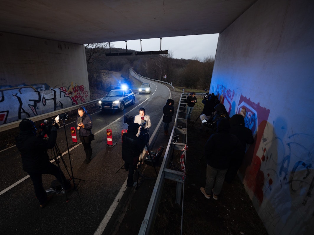 Medienvertreter stehen an einer Absperrung an der Kreisstraße 22 rund einen Kilometer von dem Tatort entfernt, an dem zwei Polizeibeamte durch Schüsse getötet wurden, und machen Liveschaltungen.