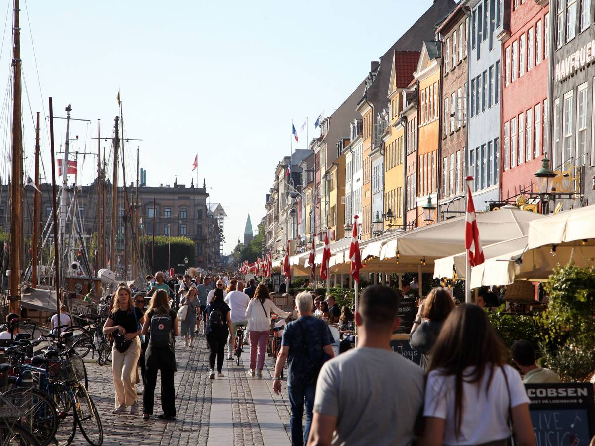 Passanten spazieren am Nyhavn entlang, dem bei Touristen beliebten Hafen mit seinen bunten Häuschen.