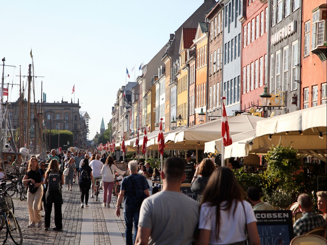 Passanten spazieren am Nyhavn entlang, dem bei Touristen beliebten Hafen mit seinen bunten Häuschen.