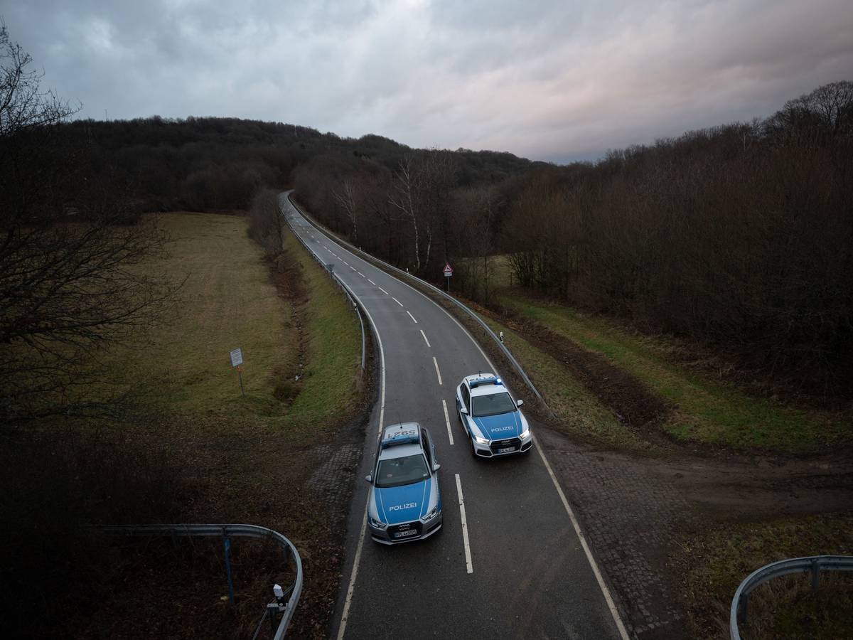 Polizeiwagen stehen an einer Absperrung an der Kreisstraße 22 rund einen Kilometer von dem Tatort, an dem ein Polizist und eine Polizeianwärterin durch Schüsse getötet wurden.