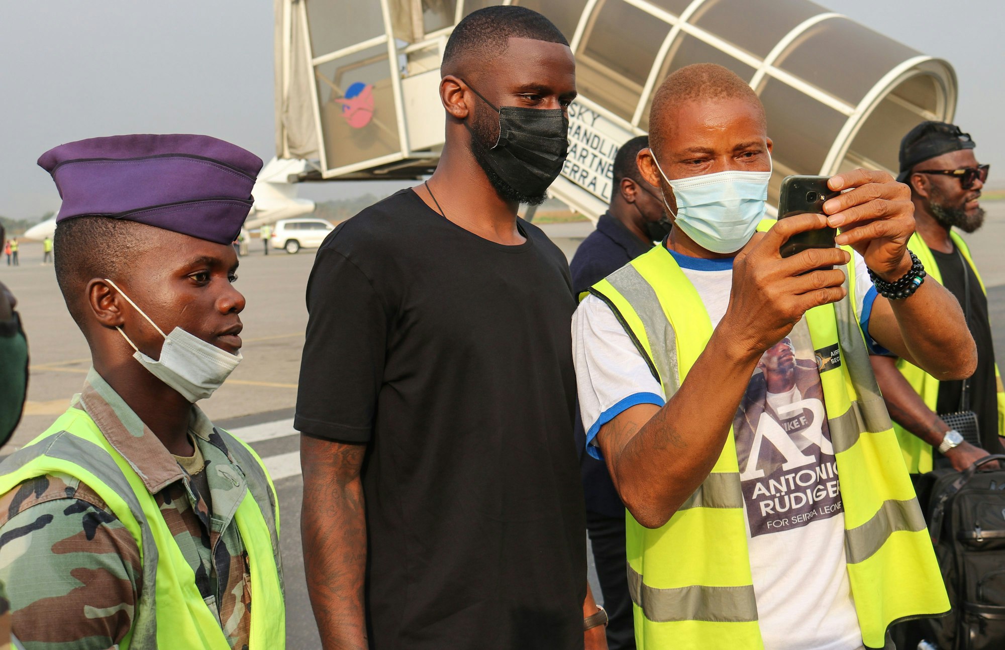 Ein Flughafen-Mitarbeiter macht auf dem Rollfeld ein Selfie mit Antonio Rüdiger.