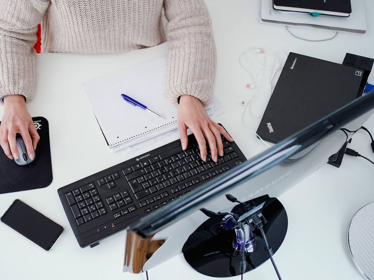 Eine Frau arbeitet in der Illustration an ihrem Schreibtisch: Sollte eine allgemeine Impfpflicht eingeführt werden, könnte es sein, dass Ungeimpfte nicht mehr beschäftigt werden können.