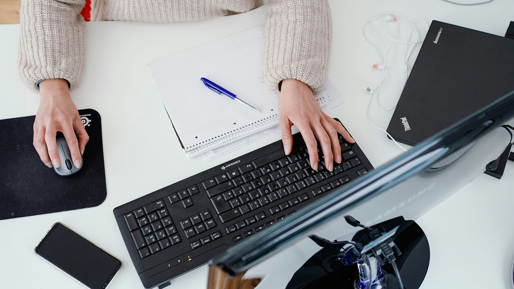 Eine Frau arbeitet in der Illustration an ihrem Schreibtisch: Sollte eine allgemeine Impfpflicht eingeführt werden, könnte es sein, dass Ungeimpfte nicht mehr beschäftigt werden können.