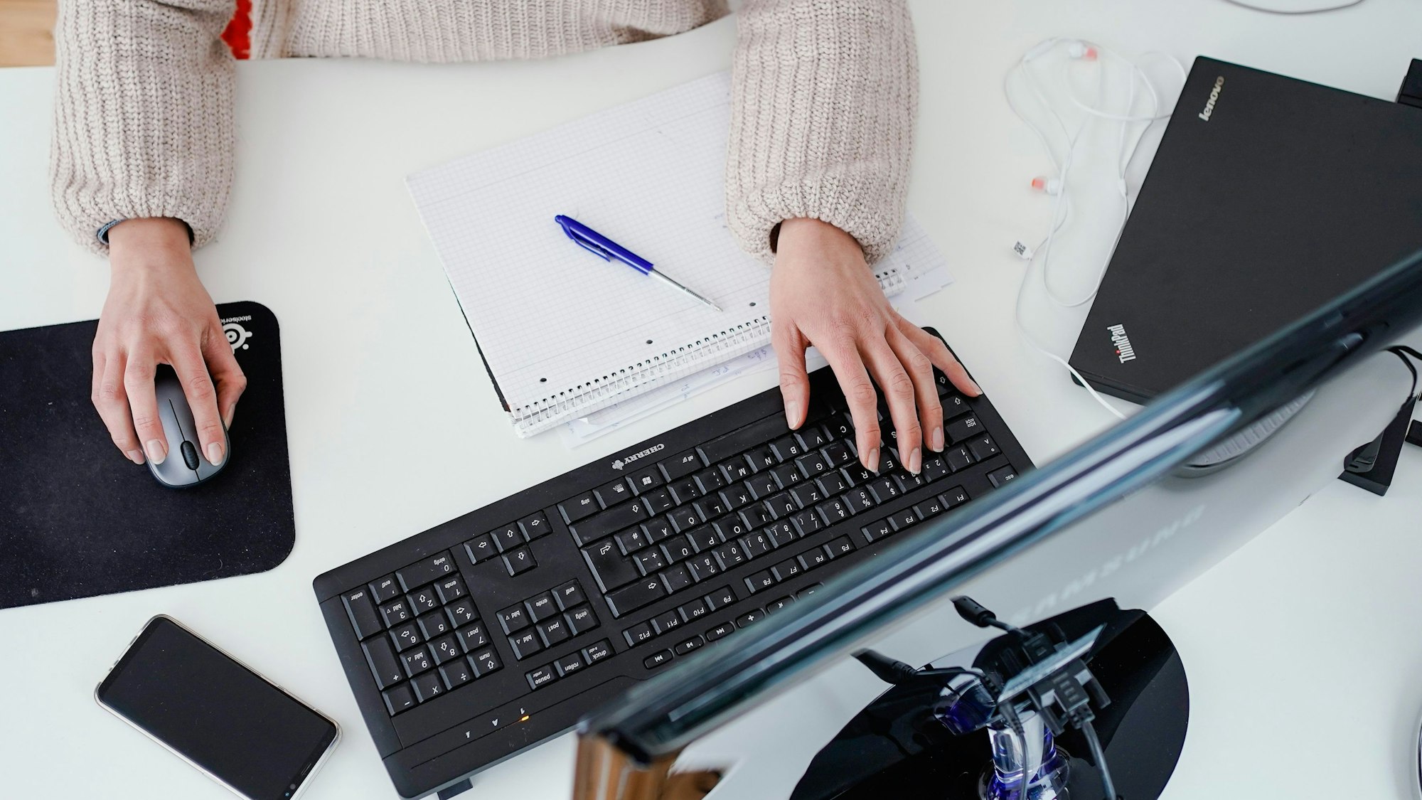 Eine Frau arbeitet in der Illustration an ihrem Schreibtisch: Sollte eine allgemeine Impfpflicht eingeführt werden, könnte es sein, dass Ungeimpfte nicht mehr beschäftigt werden können.