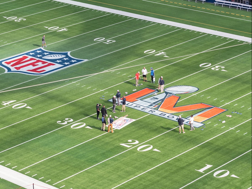 Arbeiter malen das Logo des Super Bowl LVI auf das Spielfeld im SoFi Stadium.