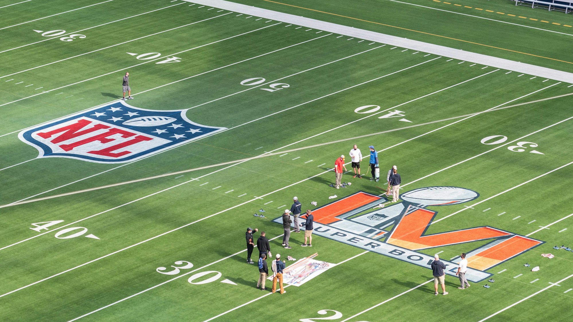 Arbeiter malen das Logo des Super Bowl LVI auf das Spielfeld im SoFi Stadium.
