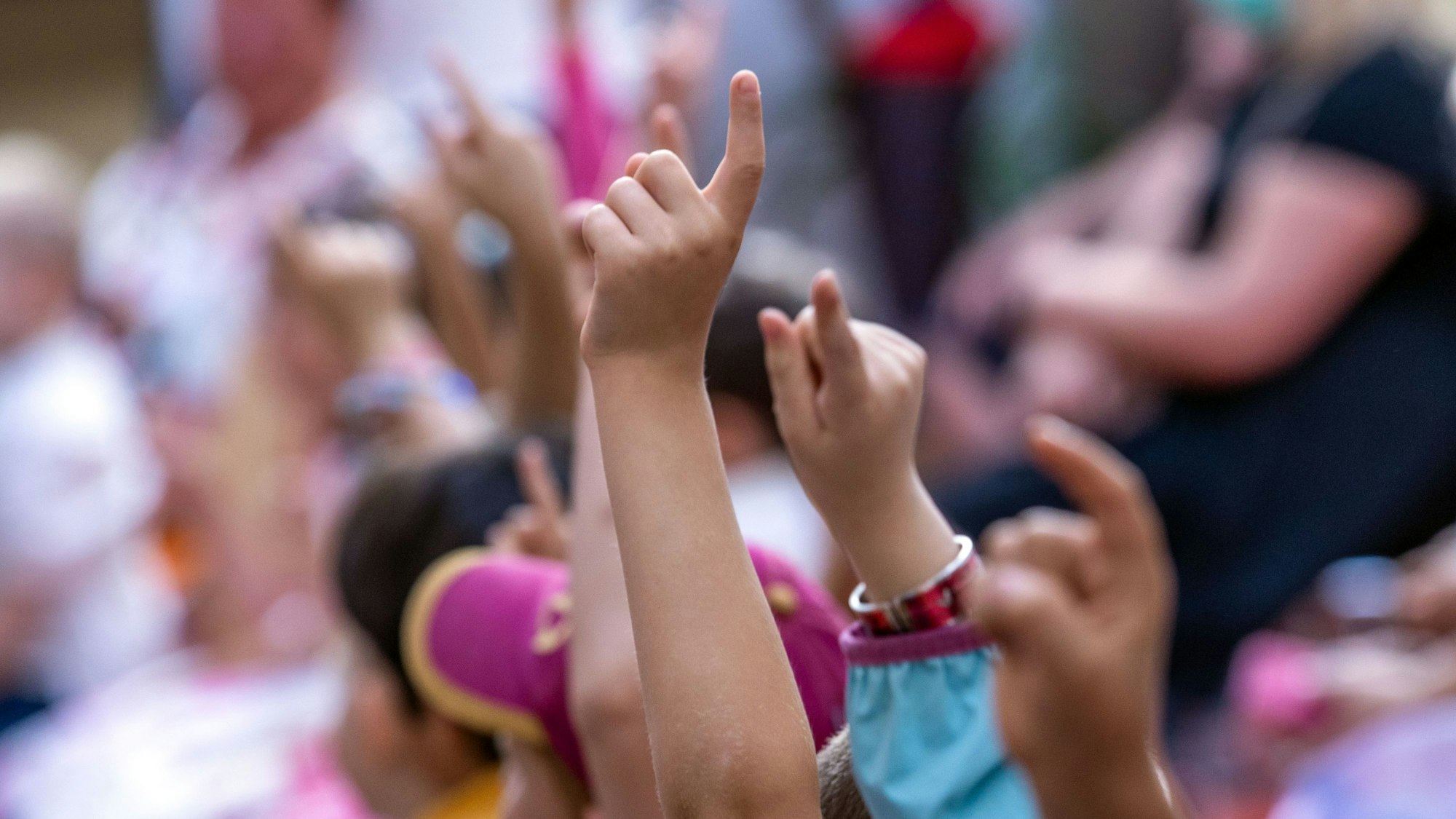 Jungen und Mädchen melden sich bei ihrer Einschulungsfeier in der Grundschule.