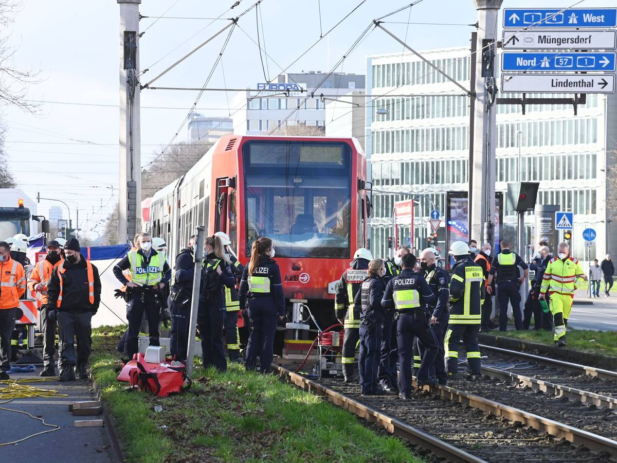 Einsatzkräfte stehen vor einer Straßenbahn, unter der eine Fußgängerin eingeklemmt wurde.