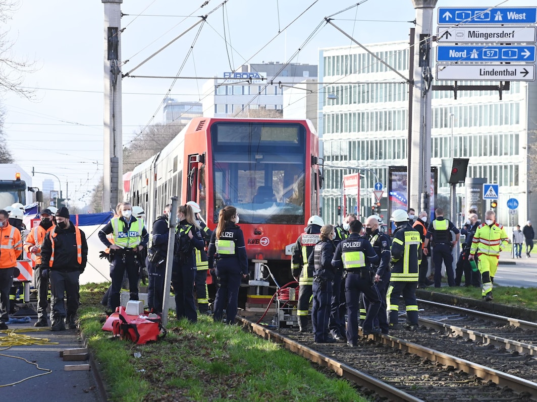 Einsatzkräfte stehen vor einer Straßenbahn, unter der eine Fußgängerin eingeklemmt wurde.