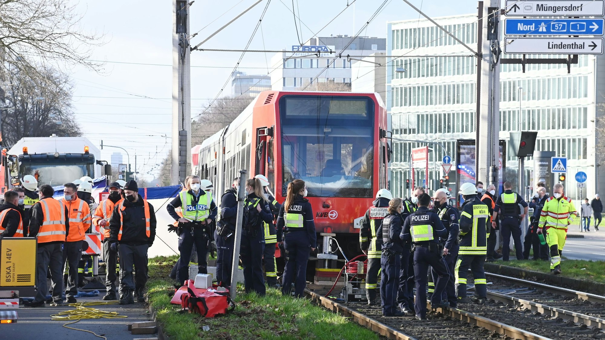 Einsatzkräfte stehen vor einer Straßenbahn, unter der eine Fußgängerin eingeklemmt wurde.