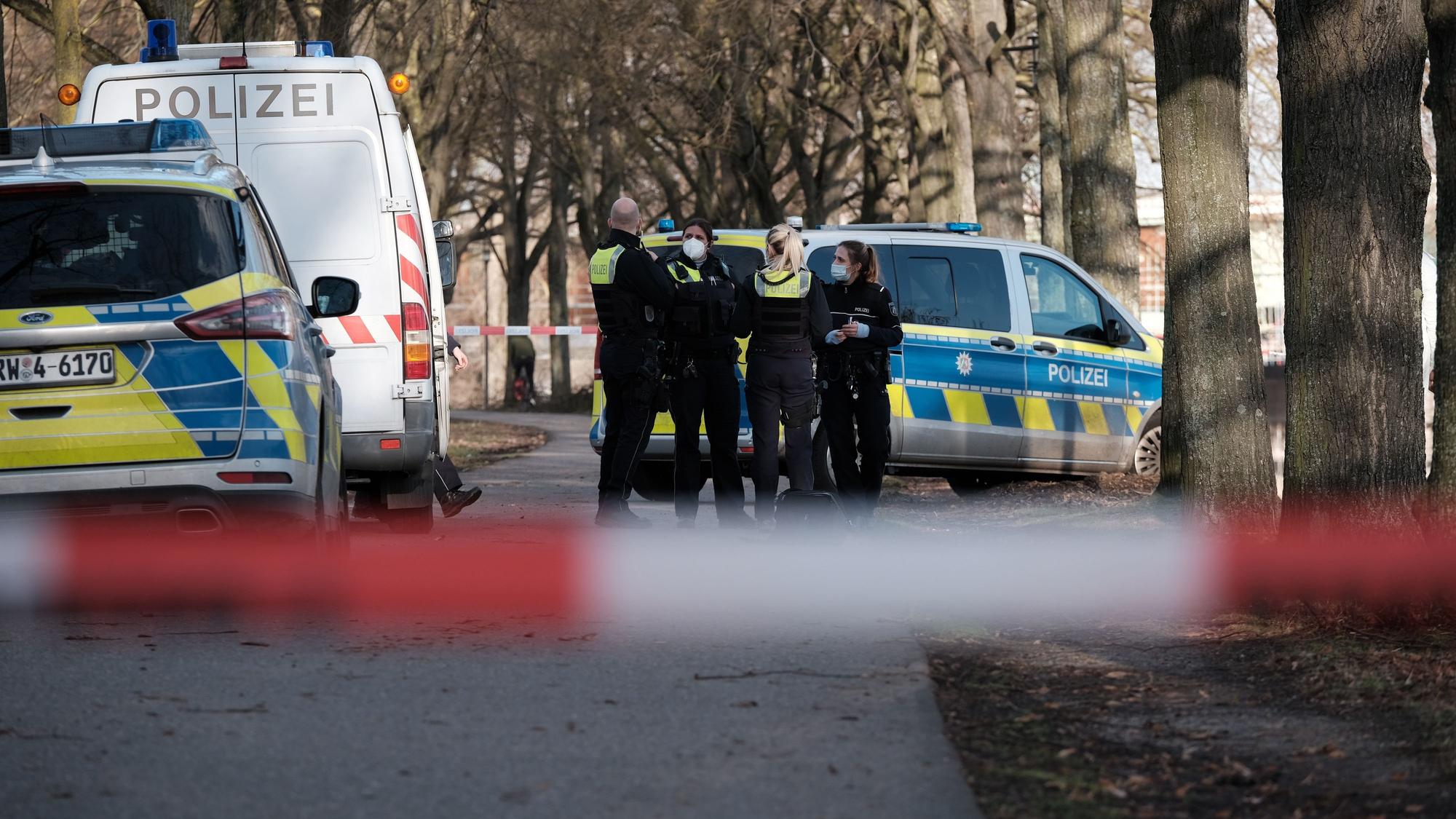Drei Polizistinnen und ein Polizei stehen neben mehreren Polizeifahrzeugen innerhalb einer Absperrung.