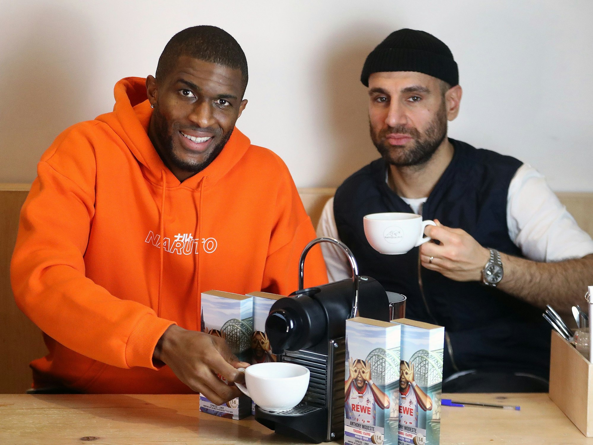 Anthony Modeste und Kaffeesaurus-Chef Rafet Aydogdu trinken Kaffee.