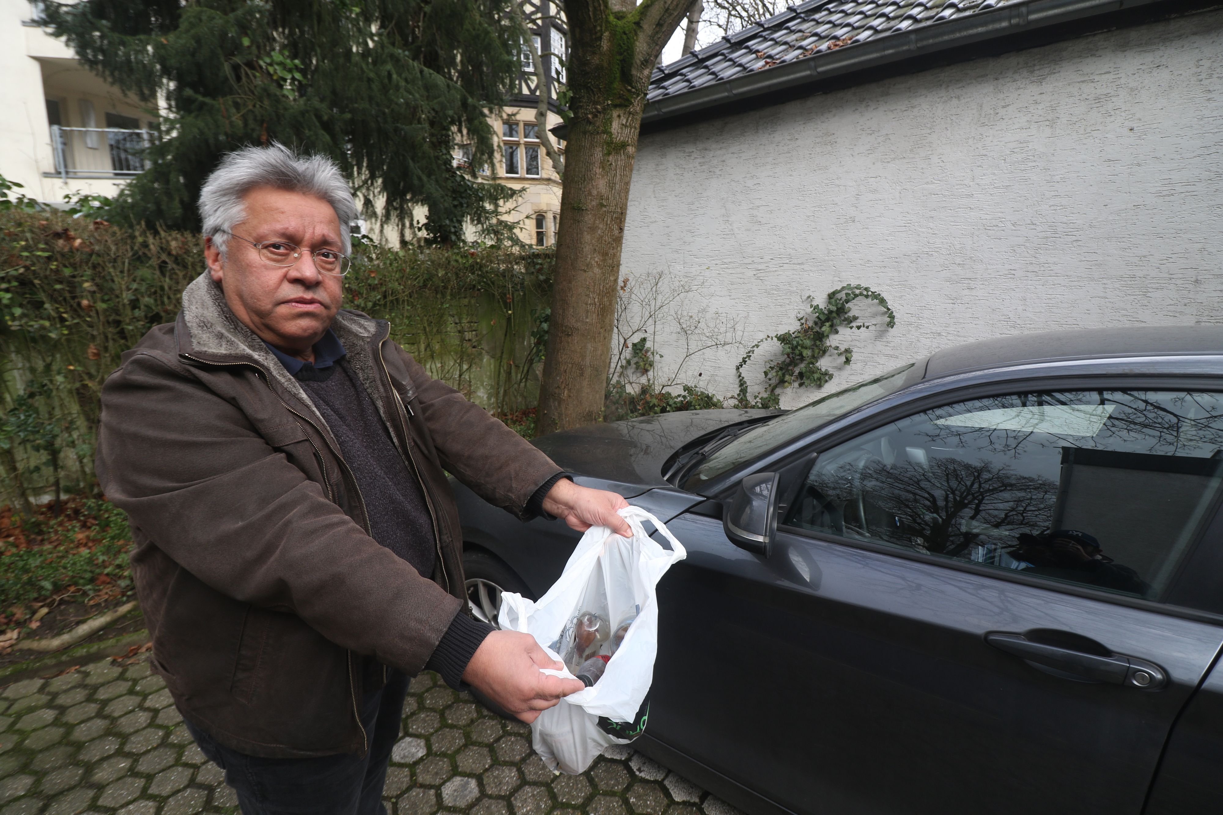 Der Kölner Mohammad Manavi hält eine Tüte voller Plastikflaschen mit Urin.