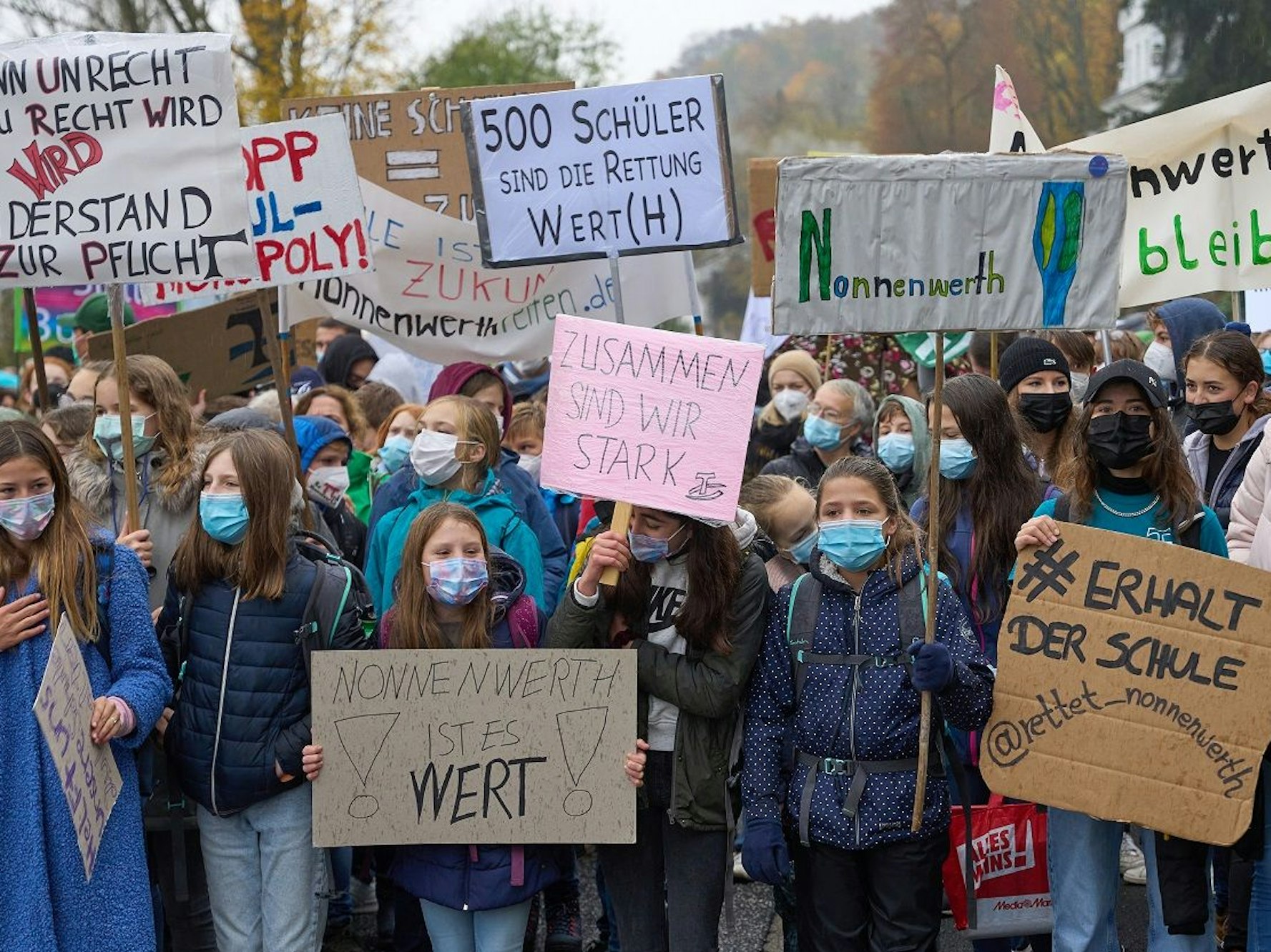 Kinder stehen dicht an dicht und halten Schilder hoch.