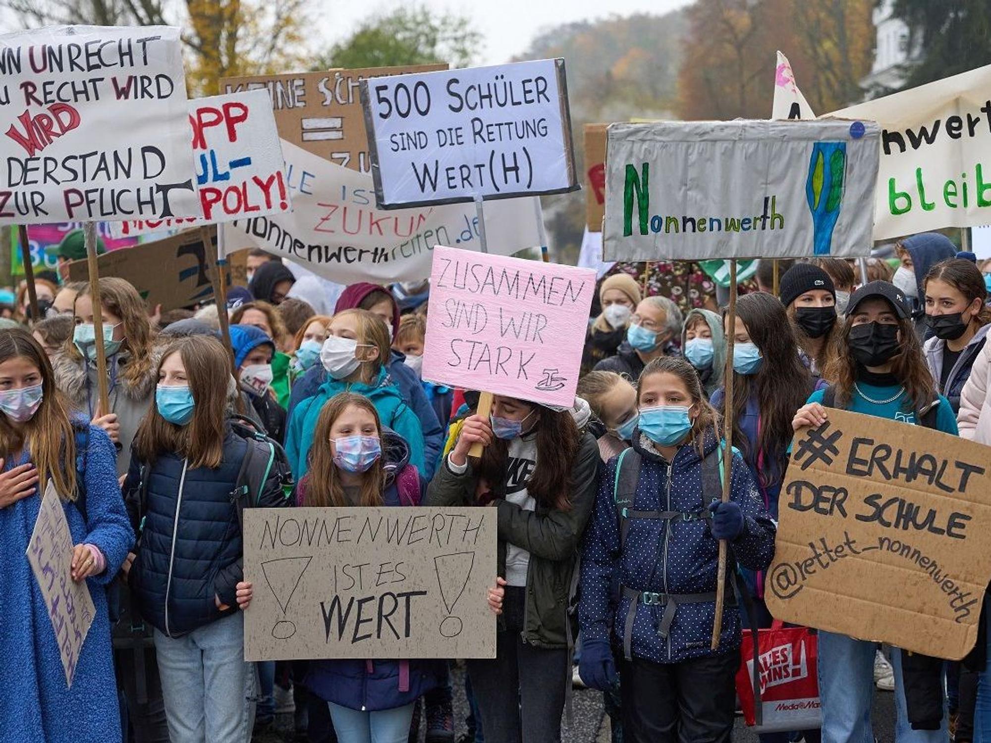 Kinder stehen dicht an dicht und halten Schilder hoch.