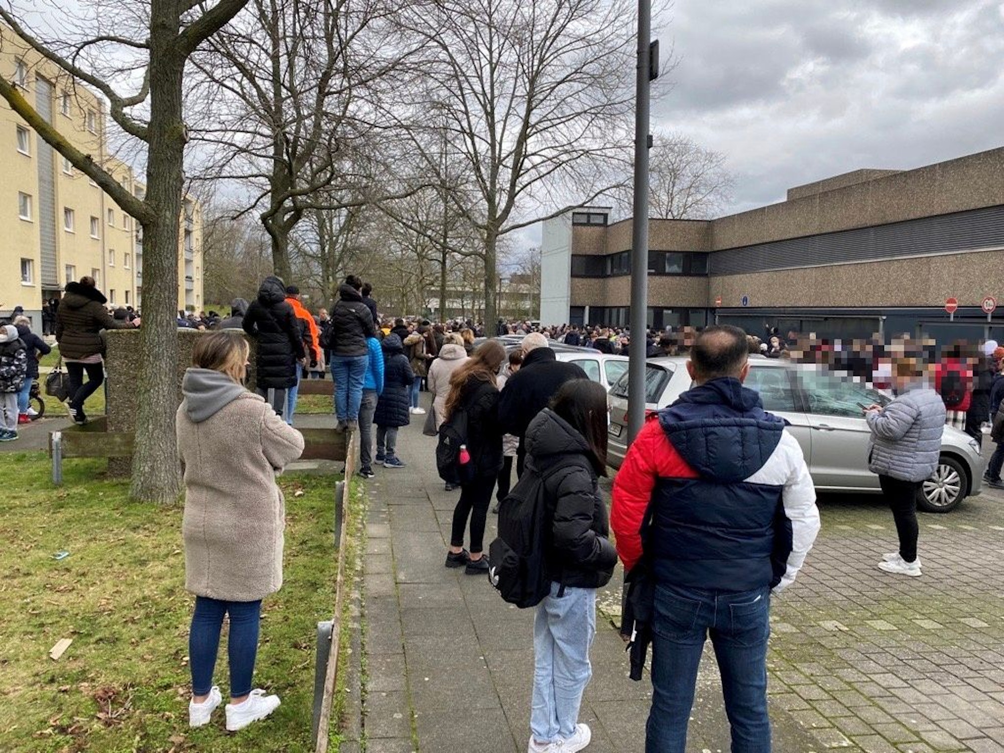 Menschen warten vor einem Gebäude.