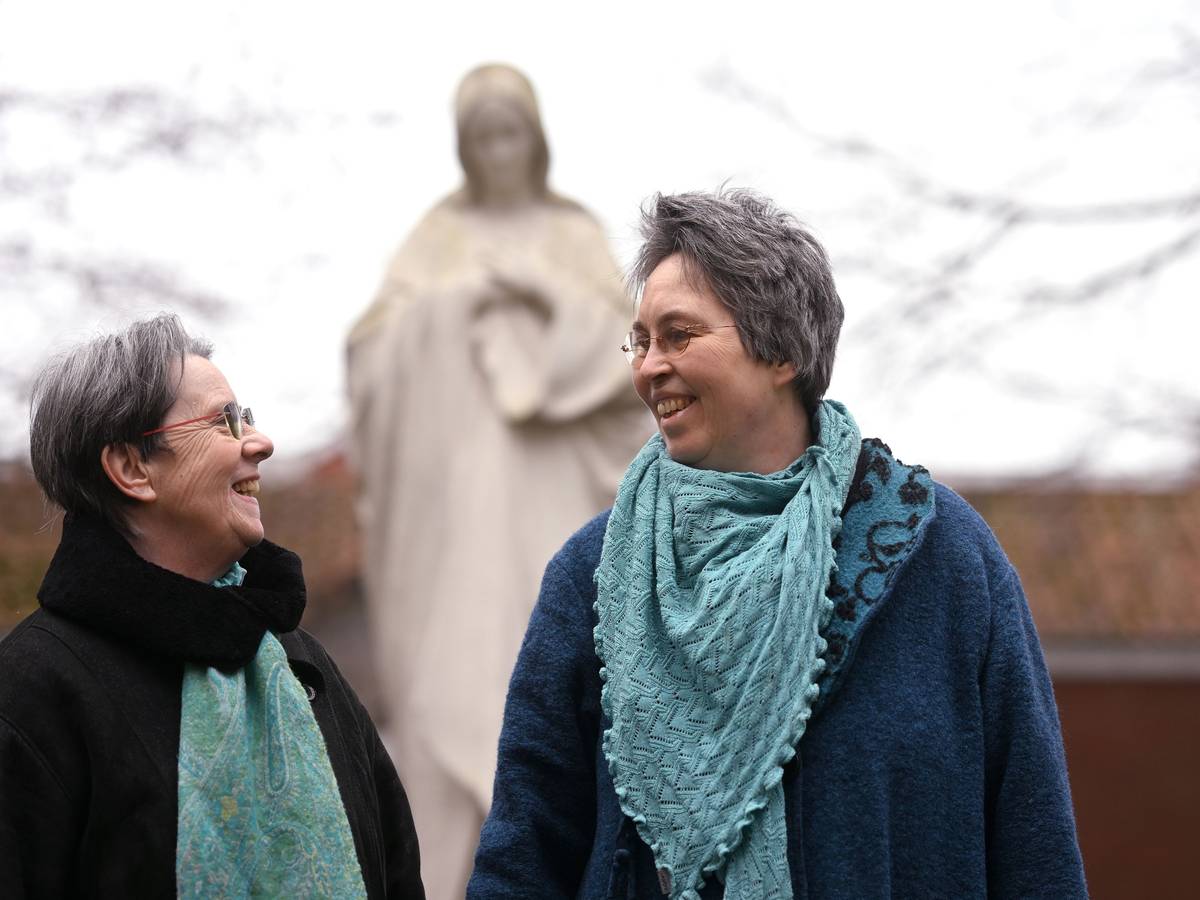 Queer in Church: Monika Schmelter (links) und Marie Kortenbusch vor einer Marienstatue eines Klosters. Die beiden sind ein Paar.