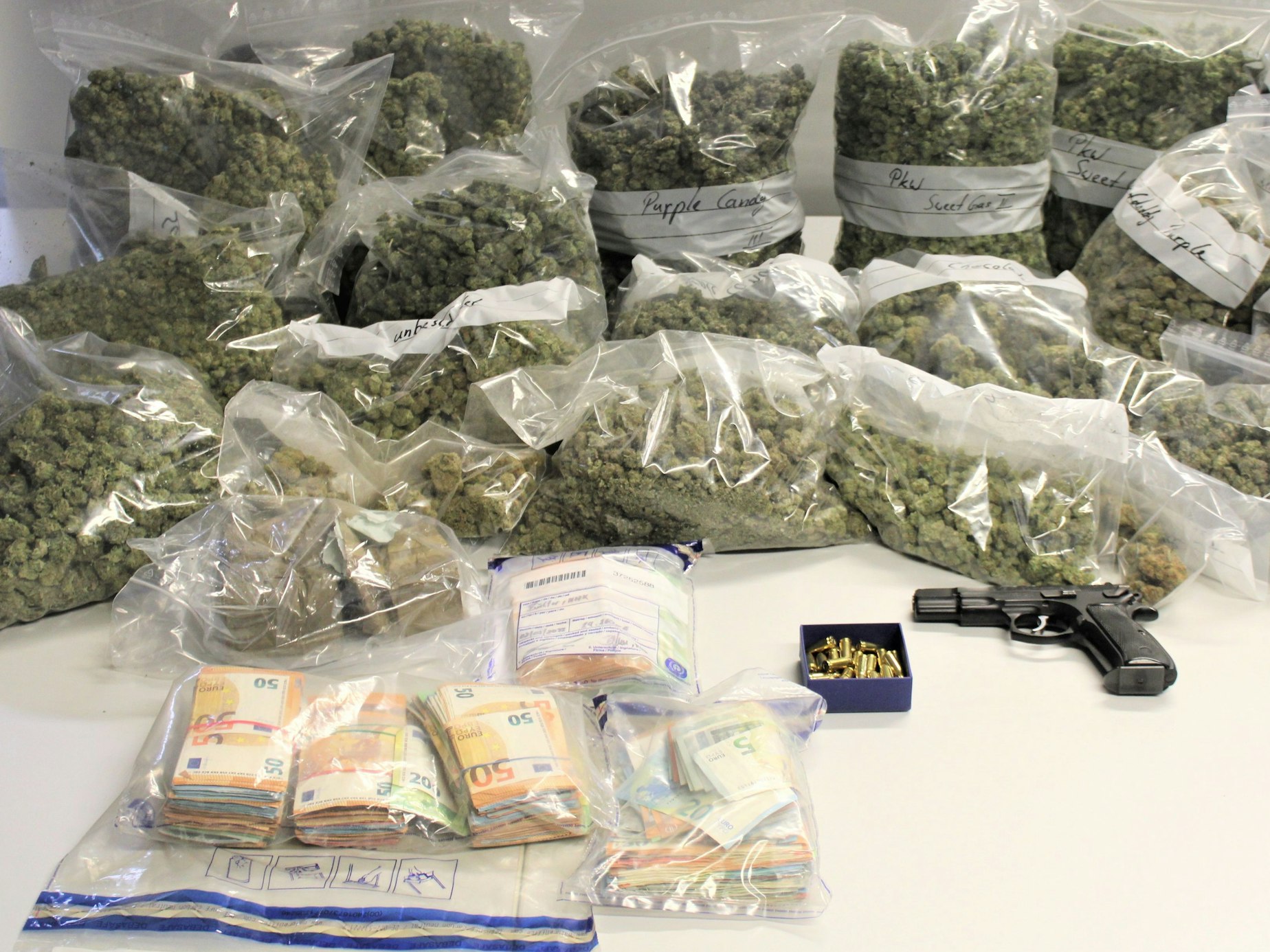 Eine Menge Drogen, Bargeld und eine Waffe auf einem Tisch.