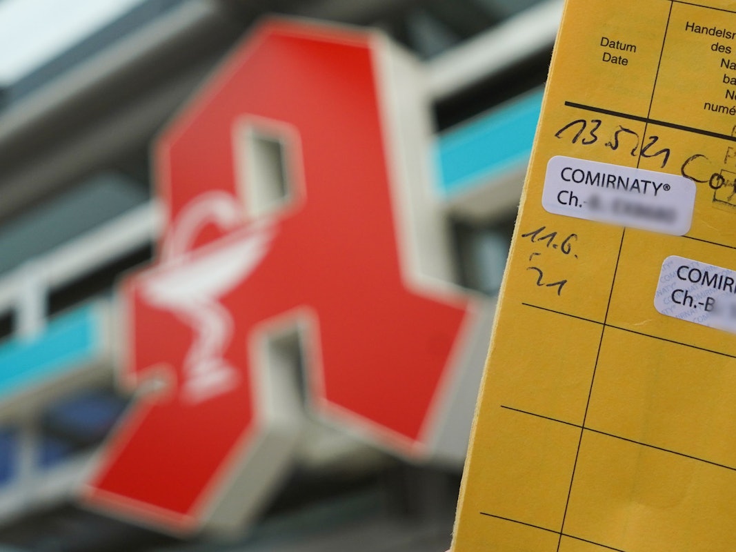 Impfausweis vor dem Logo einer Apotheke.