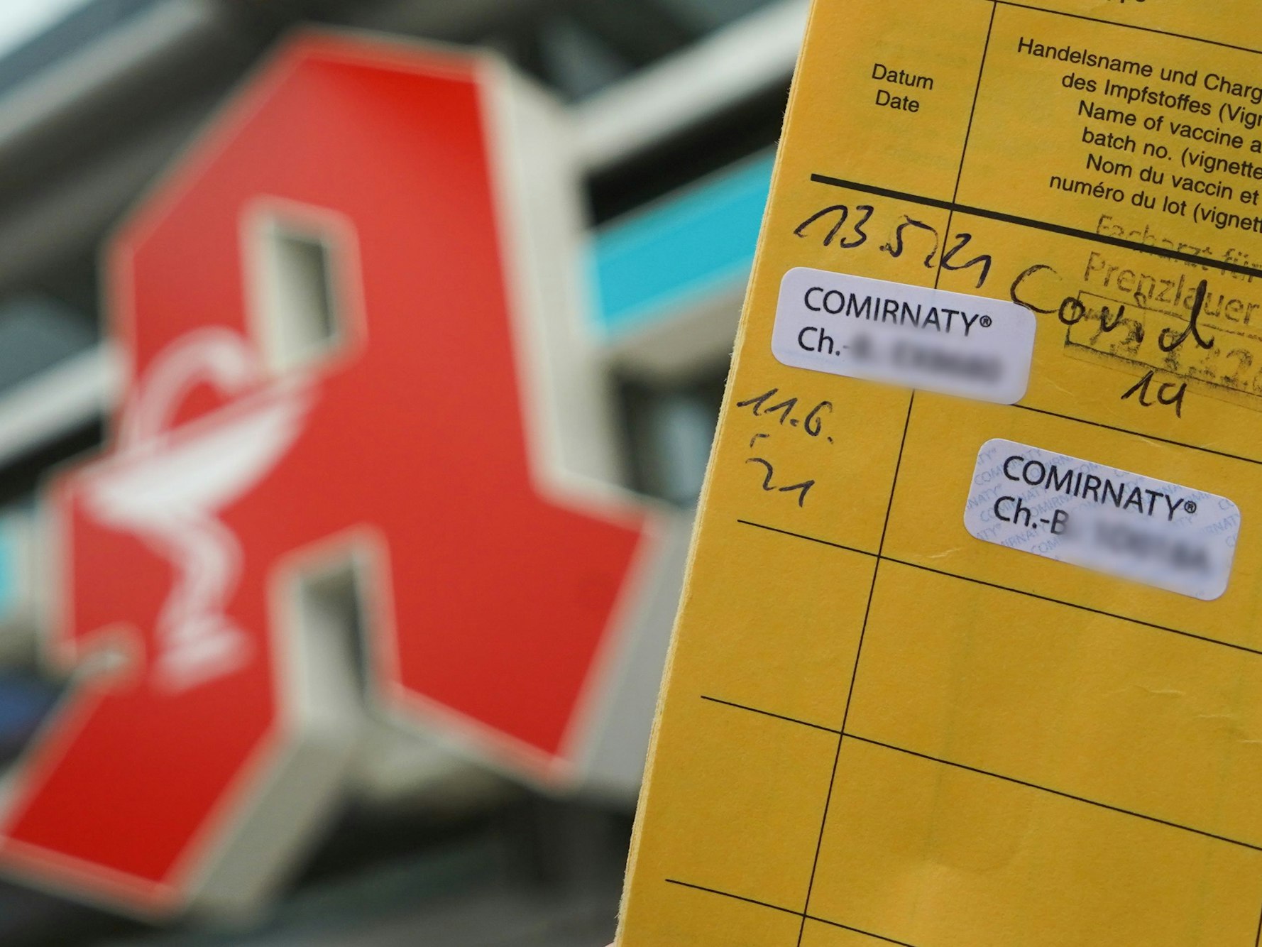 Impfausweis vor dem Logo einer Apotheke.