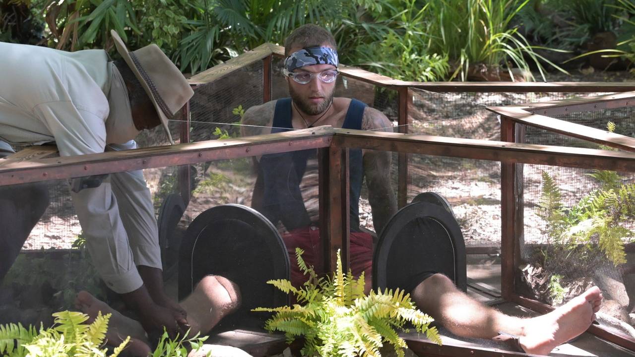 Das Foto zeigt Dschungelcamp-Finalist Filip Pavlovic während einer Dschungelprüfung auf dem Boden sitzend mit einer Schutzbrille