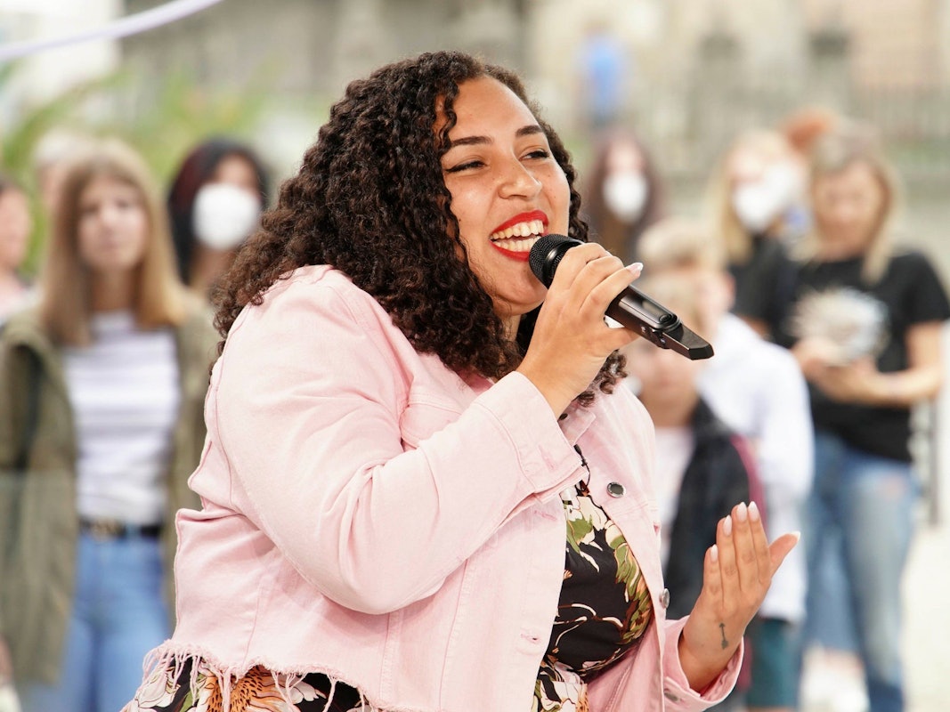 Das Foto zeigt die DSDS-Teilnehmerin Chantal Yancey, die mit einem Mikrofon vor dem Mund einen Song performt.