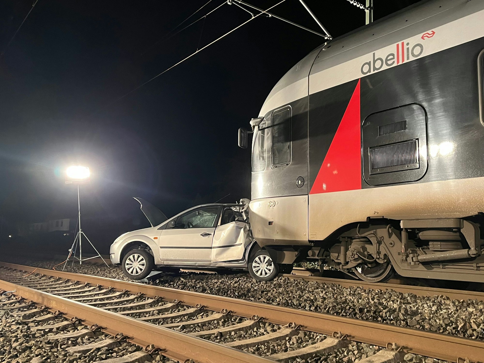 Ein Auto steht auf Gleisen vor einem Zug.