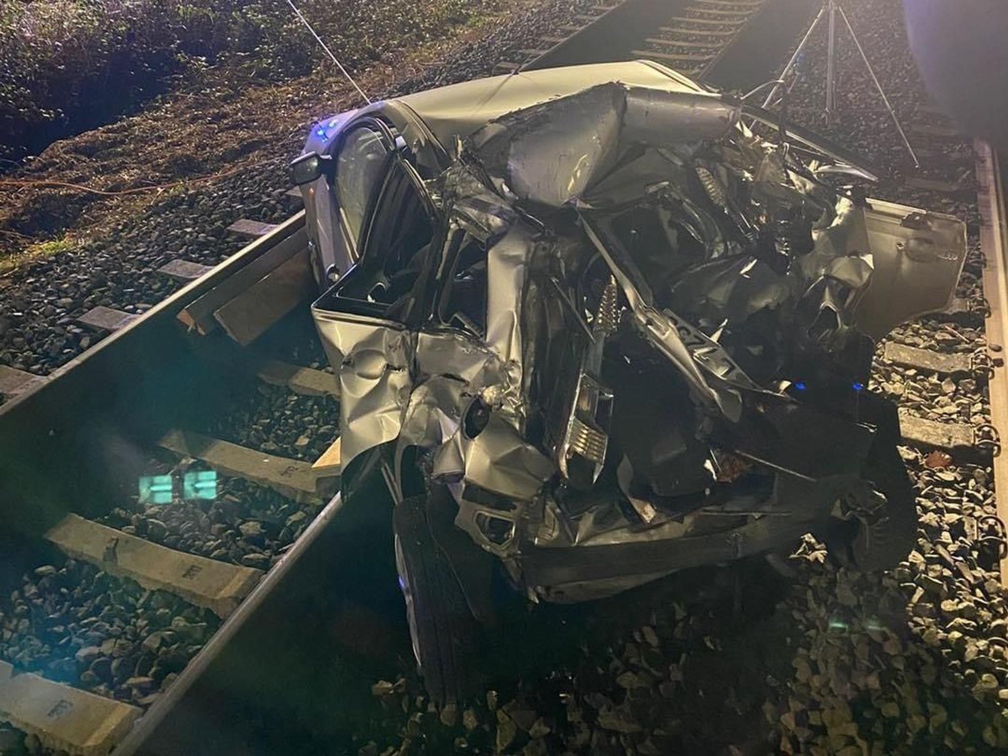 Ein demoliertes Auto steht nach einem Unfall auf Gleisen.