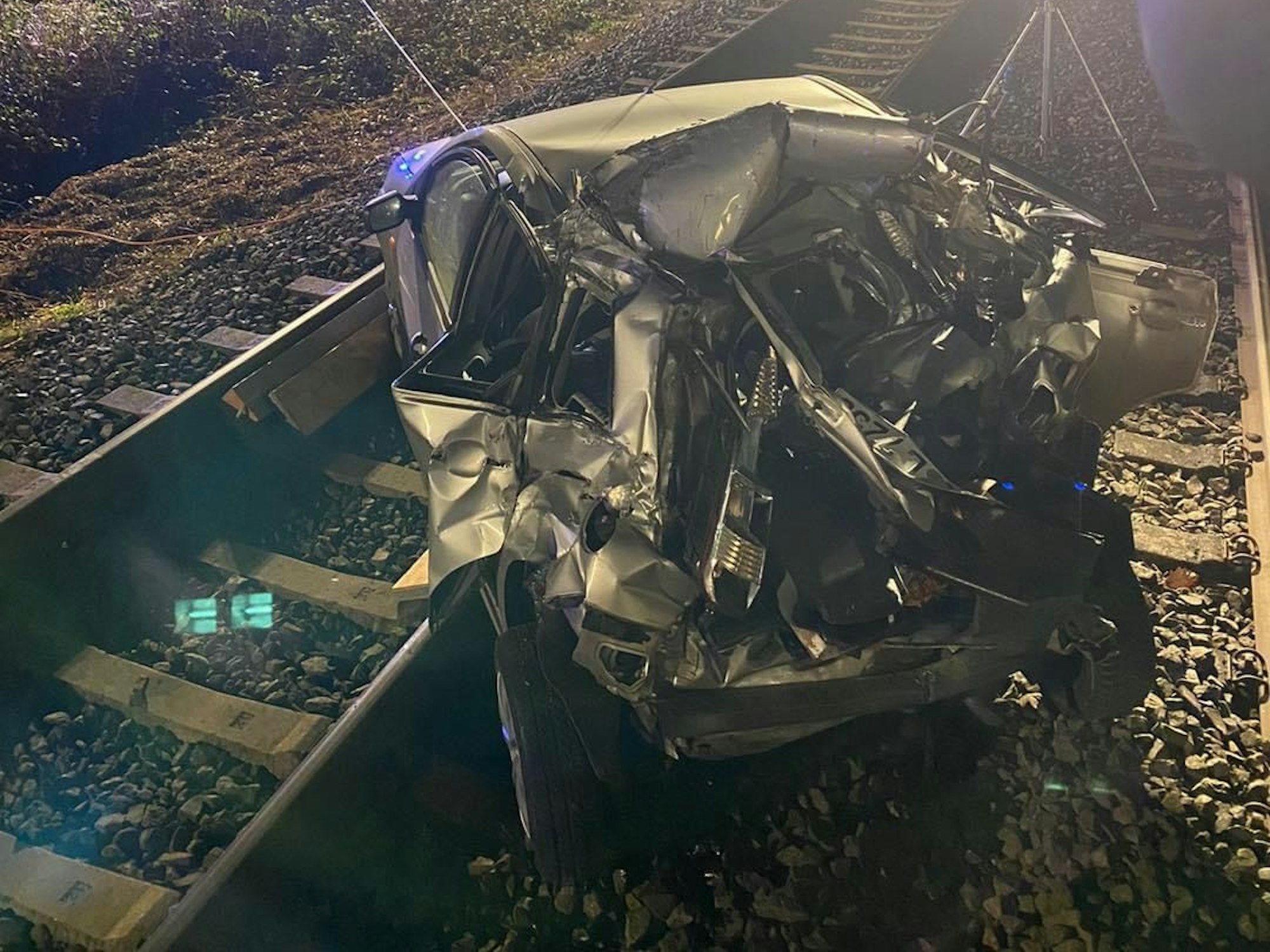 Ein demoliertes Auto steht nach einem Unfall auf Gleisen.