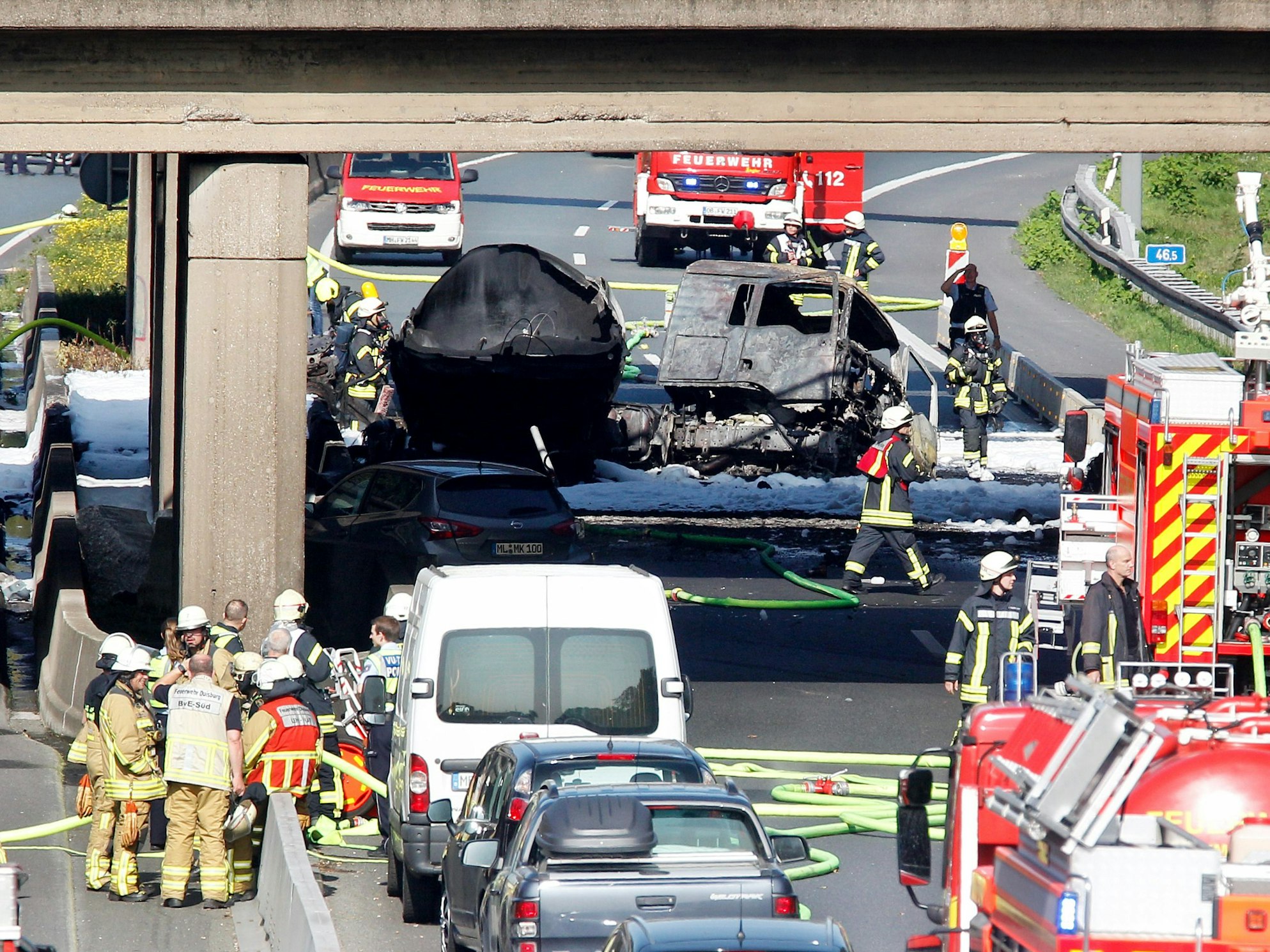 Nordrhein-Westfalen, Mülheim: Feuerwehrleute stehen an dem ausgebrannten Tanklaster auf der A40.