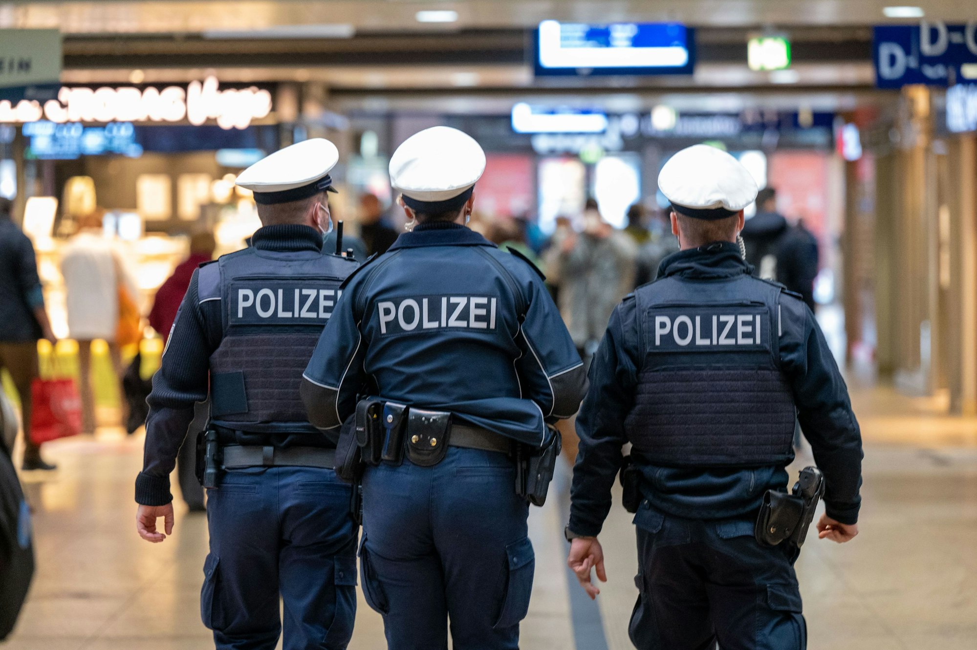 Drei Polizeibeamte laufen durch den Kölner Hauptbahnhof.