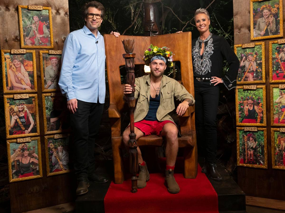 In diesem vom Fernsehsender RTL zur Verfügung gestellten Bild sitzt der neue "Dschungelkönig" Filip Pavlovic (M) auf seinem Thron. Daneben stehen die Moderatoren der Sendung Daniel Hartwich (l) und Sonja Zietlow. Pavlovic hat das Finale des RTL-Dschungelcamp 2022 gewonnen.