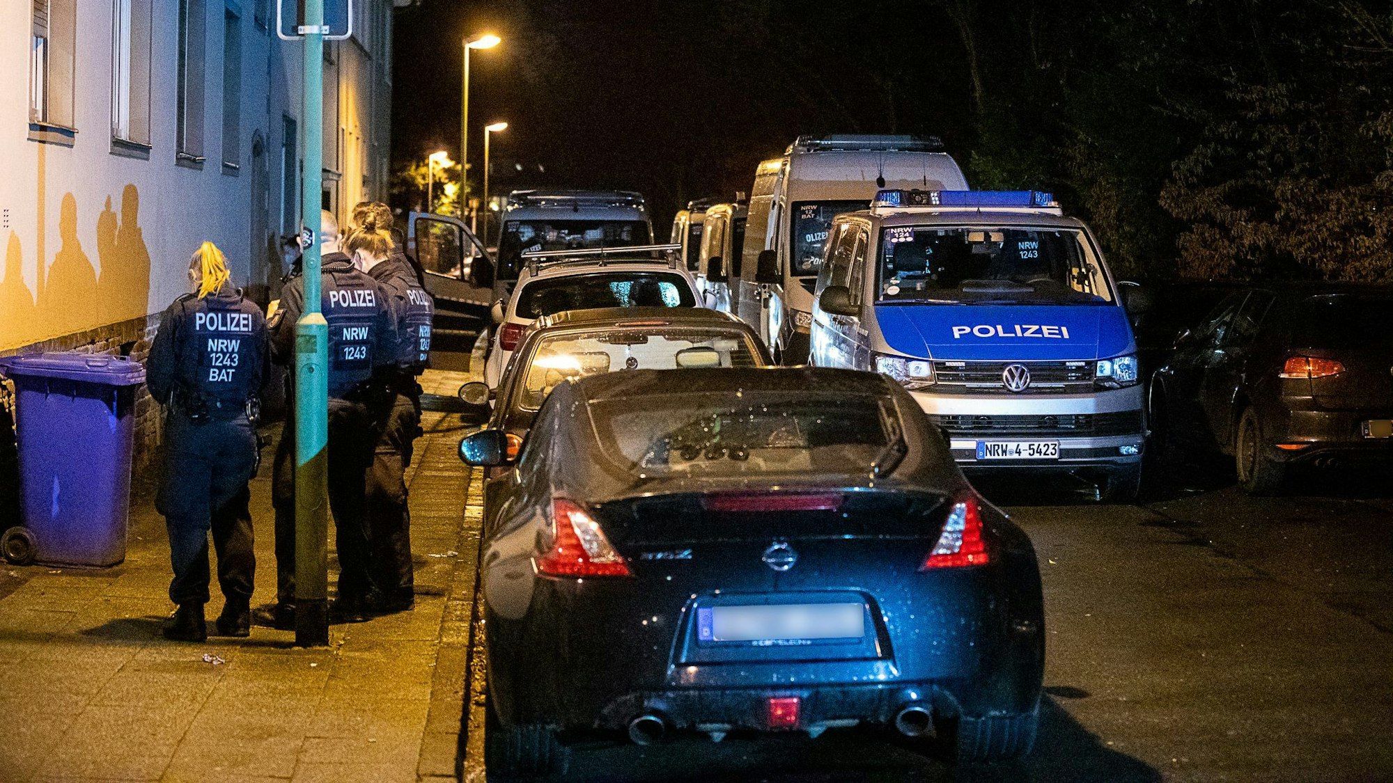 Polizei steht vor eine Gebäude, das durchsucht wird.