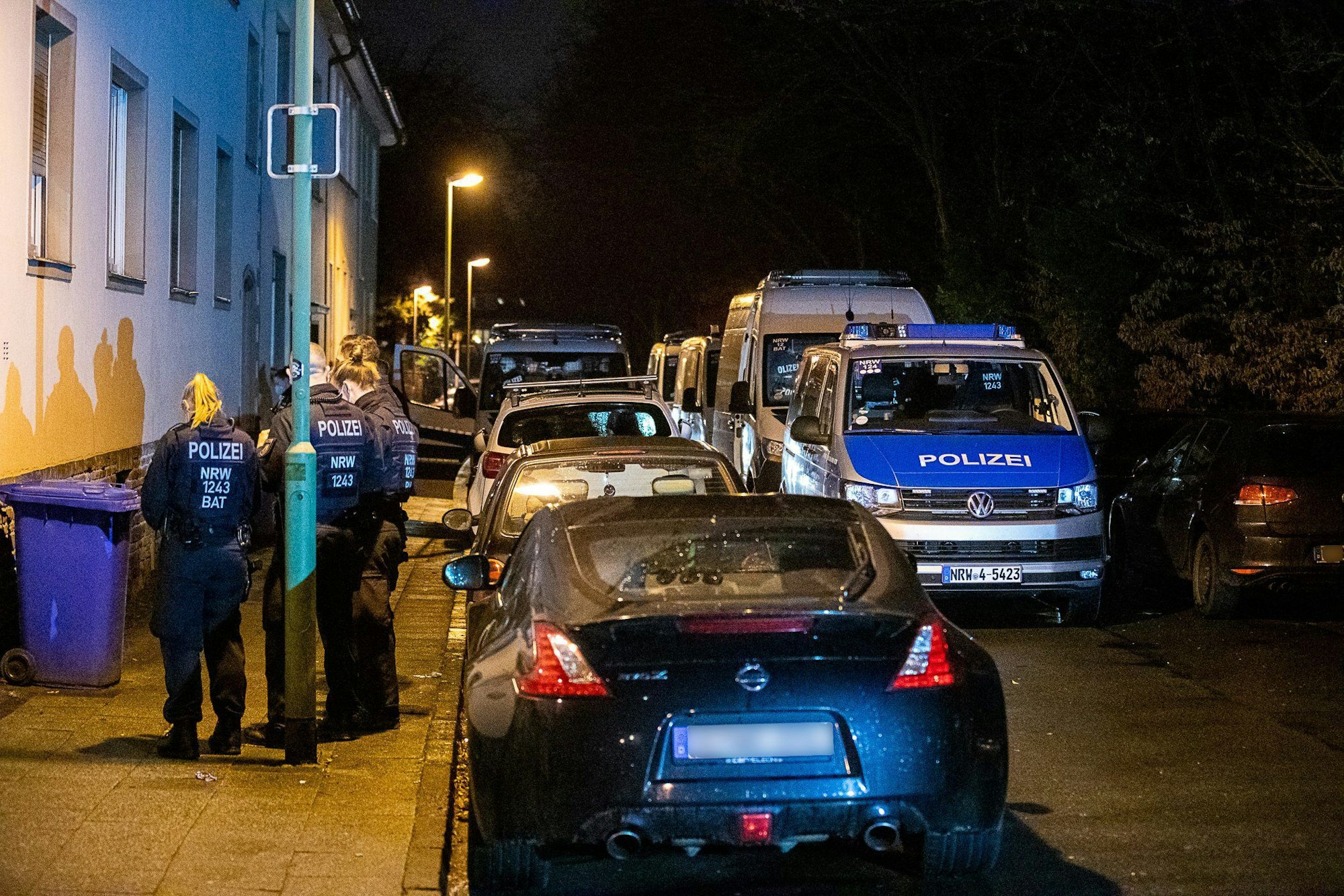 Polizei steht vor einem Gebäude, das durchsucht wird.