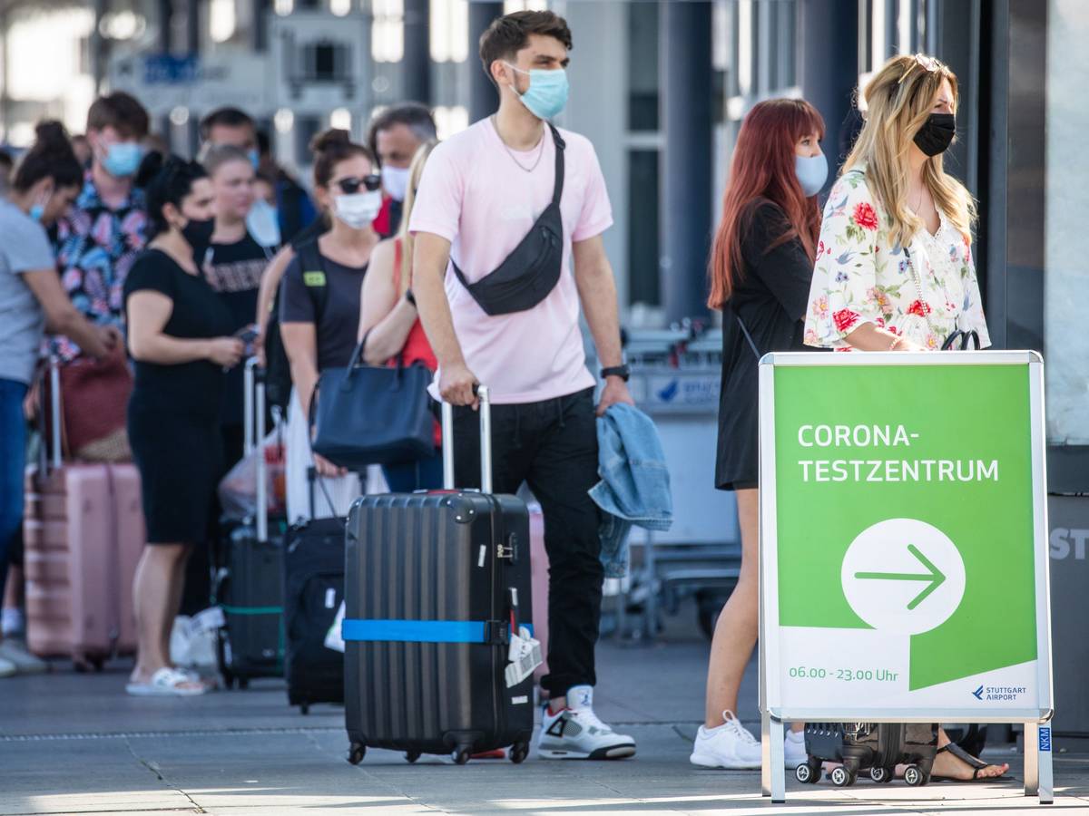 Reiserückkehrer stehen mit Mundschutz vor dem Corona-Testzentrum am Flughafen Stuttgart.