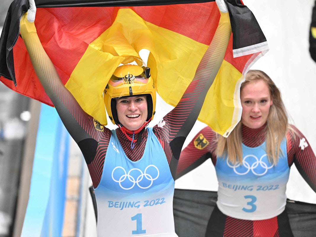 Natalie Geisenberger jubelt mit der deutschen Flagge.