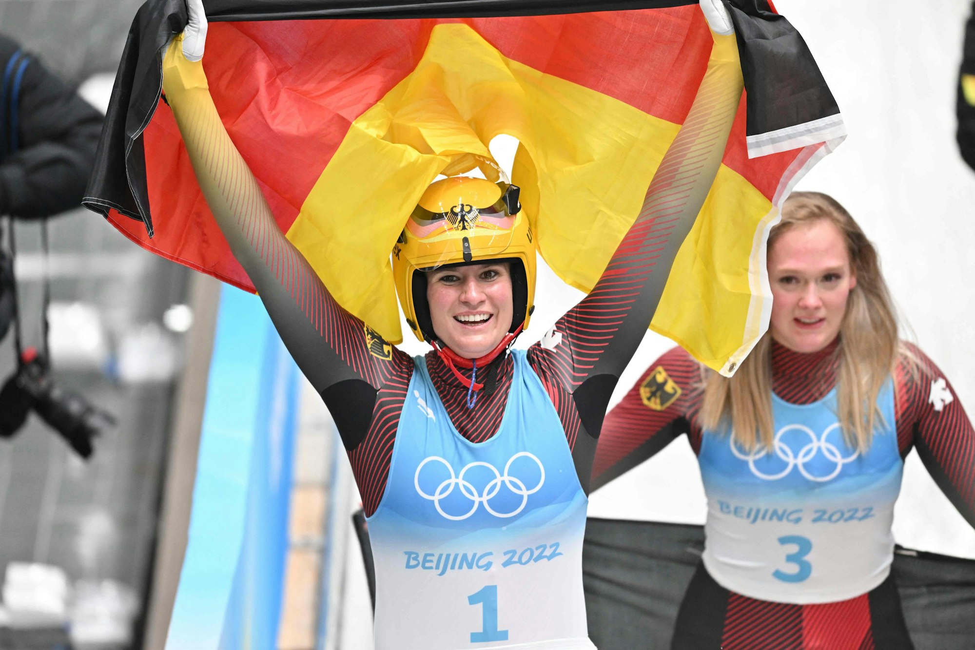 Natalie Geisenberger jubelt mit der deutschen Flagge.