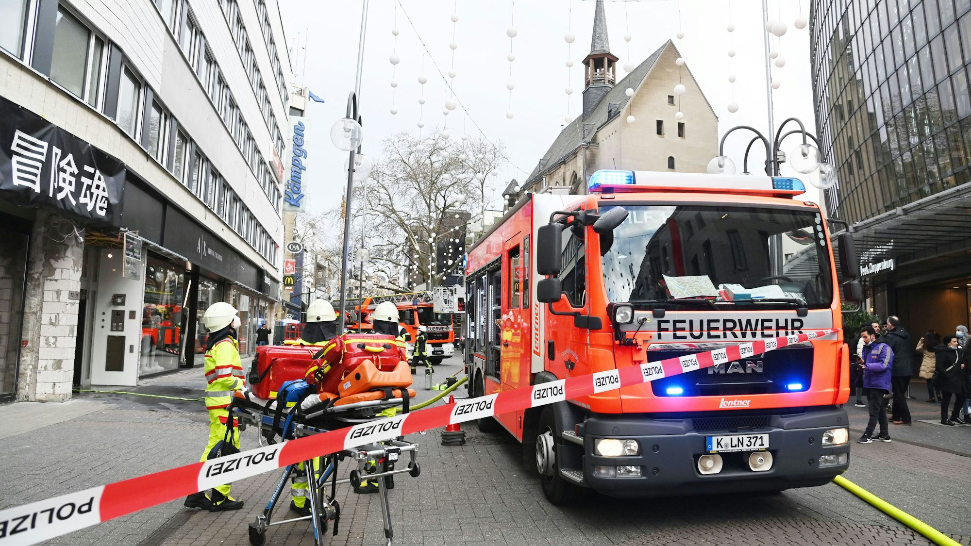 Ein Feuerwehrfahrzeug sowie mehrere Einsatzkräfte stehen auf der Schildergasse, die Straße ist mit Flatterband zum Teil abgesperrt.