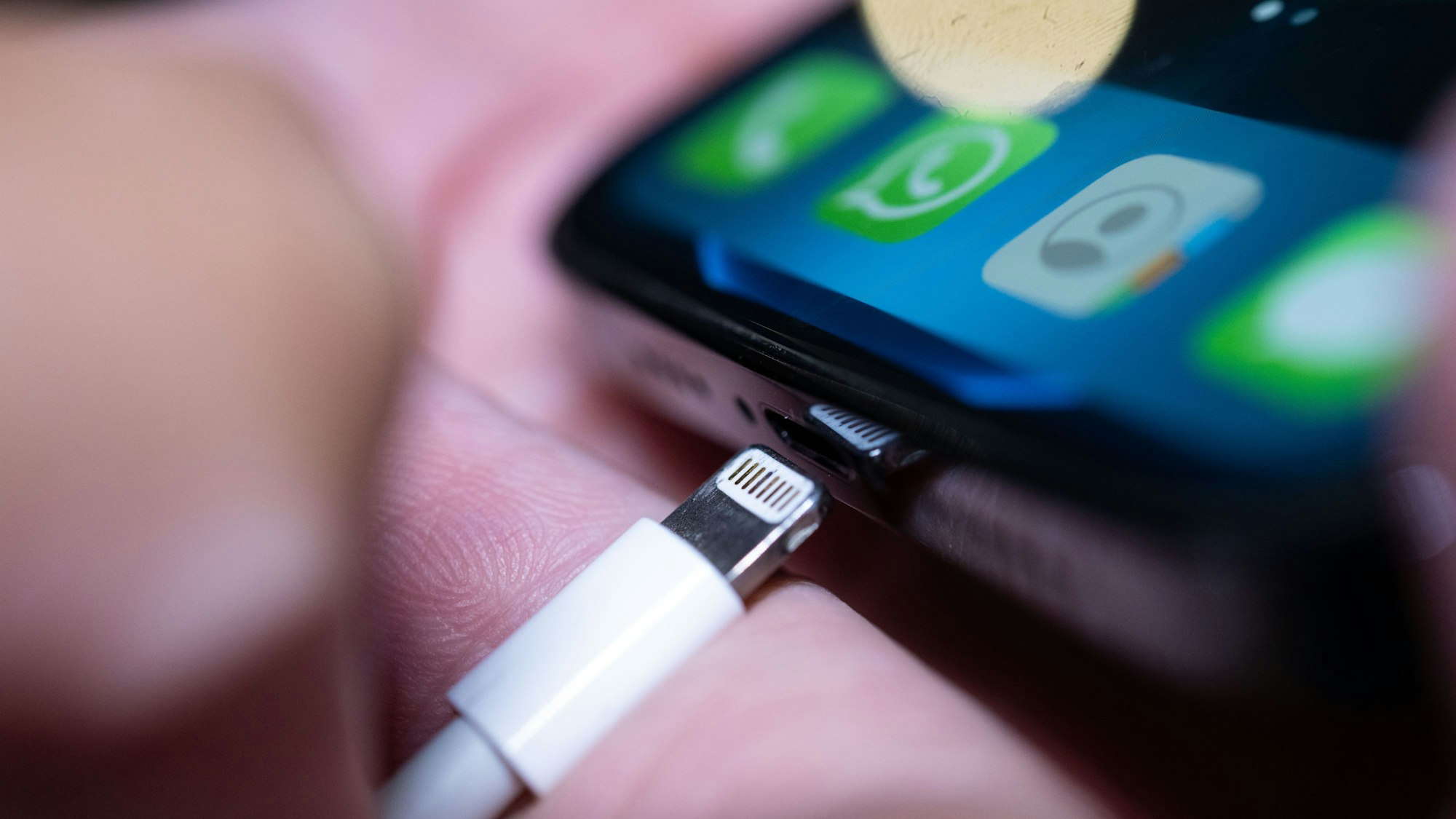 Ein Lightning-Ladestecker wird in ein Apple iPhone gesteckt.