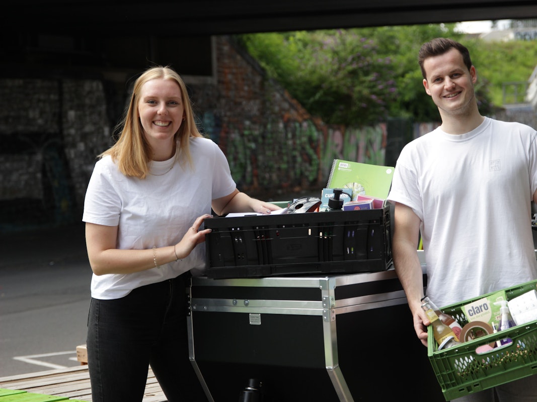 Anne Kronshage und Salomon Bohlen tragen Kisten und schauen in die Kamera.